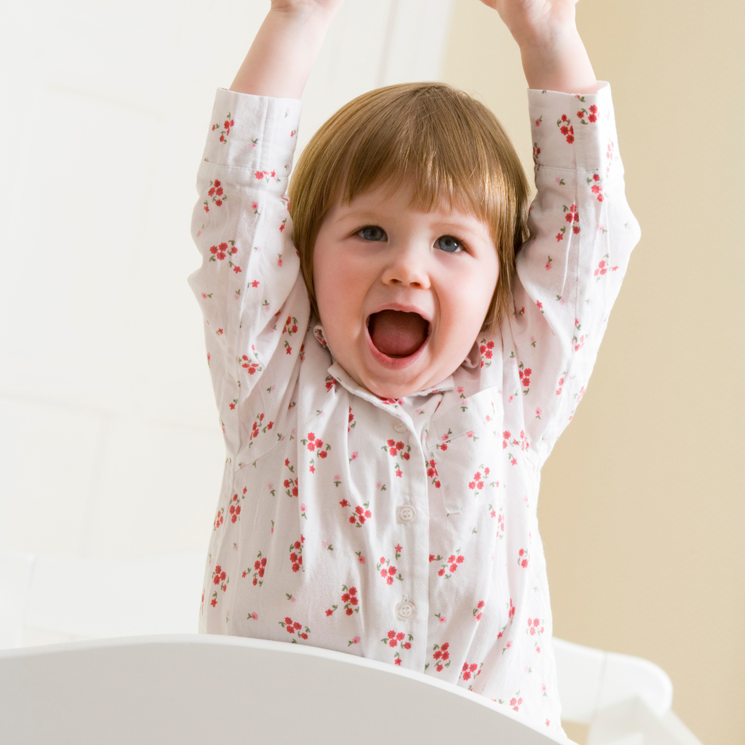 happy toddler standing in bed